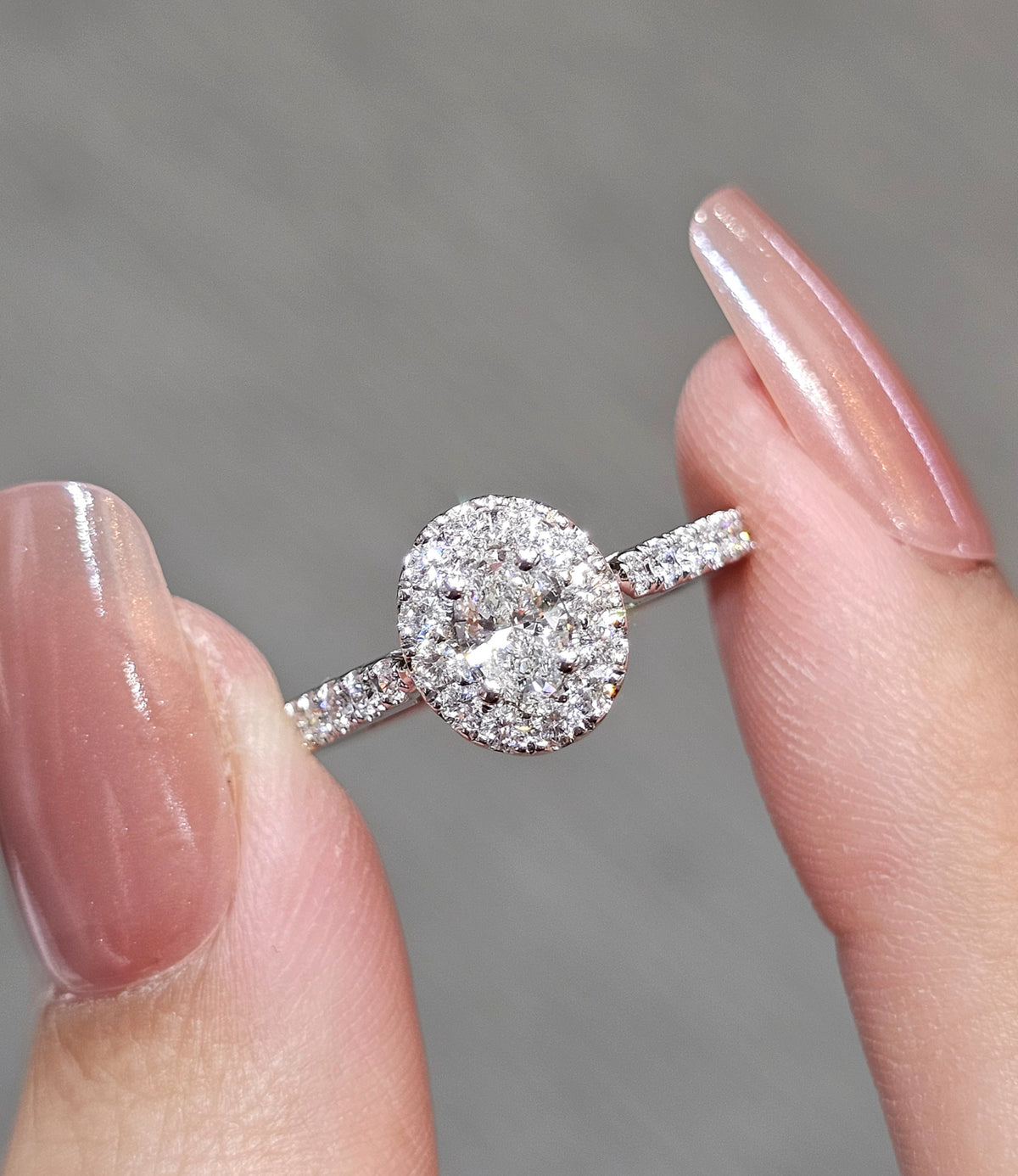 A close-up of a diamond halo ring , set against a soft gray background.